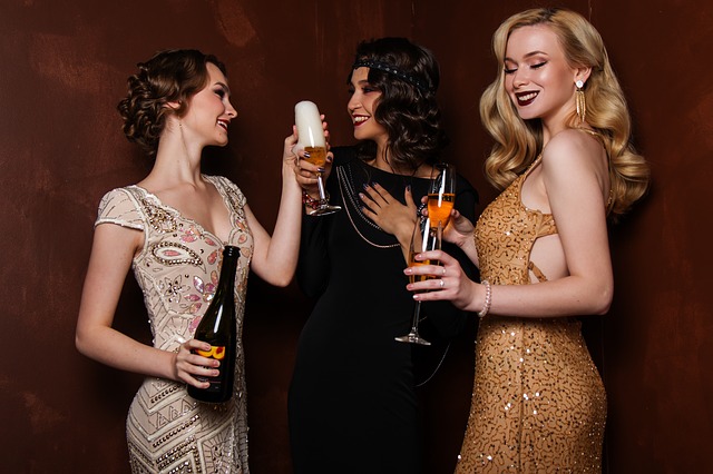 Tři ženy ve společenských šatech, připíjející si šampaňským.jpg